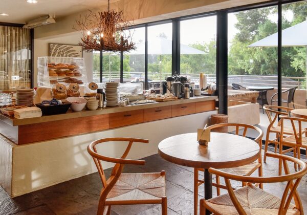 Buffet breakfast set up on large table surrounded by tables and chairs with large glass doors to patio