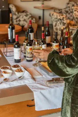 Wine and cheese set up on large table surrounded by tables and chairs with large glass doors leading to patioMillValleyInn2025ShotByTheNomadicPeople-95.jpg