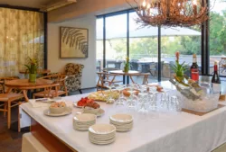 Wine and cheese set up on large table surrounded by tables and chairs with large glass doors leading to patiowine-reception.jpg